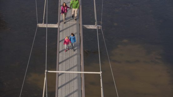 Familie auf schmaler Brücke über Wasser