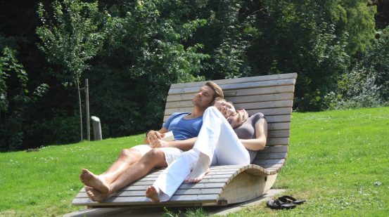Frau und Mann entspannen auf Relaxliegen im Kurpark am See in Bad Bodenteich