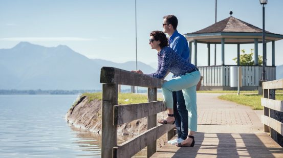 Frau und Mannj blicken auf den See auf einer kleinen Holzbrücke